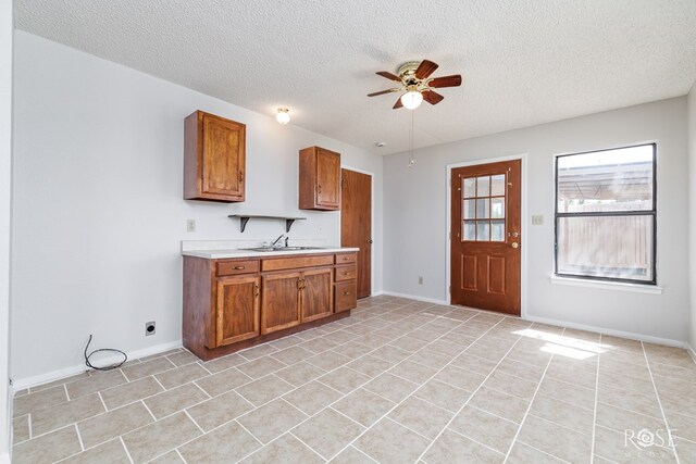5821 Davenport Dr, San Angelo, TX 76901 - kitchen featuring a ceiling fan, light countertops, brown cabinetry, a sink, and a textured ceiling