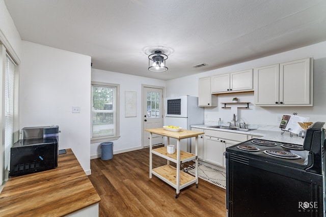 kitchen featuring sink, black range with electric stovetop, white refrigerator, white cabinets, and dark hardwood / wood-style flooring