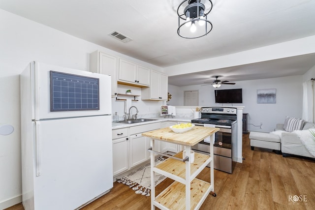 kitchen featuring sink, white cabinets, stainless steel range with electric stovetop, white fridge, and light hardwood / wood-style floors