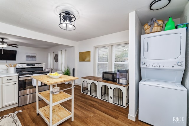 kitchen featuring dark wood-type flooring, stainless steel range with electric stovetop, stacked washer and clothes dryer, and white cabinets