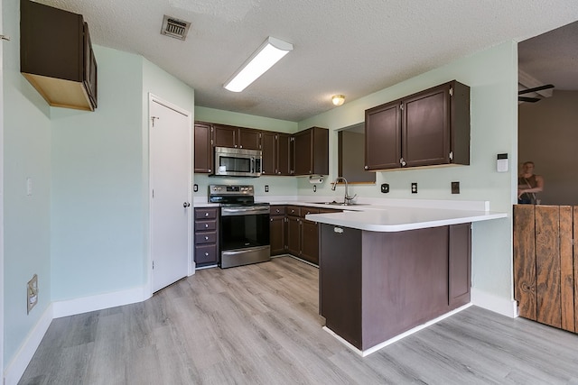 1605 Amberton Pkwy, San Angelo, TX 76901 - kitchen with appliances with stainless steel finishes, light wood-style flooring, dark brown cabinetry, and a textured ceiling