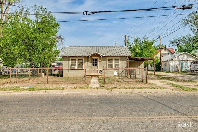 view of front facade with metal roof, a carport, a fenced front yard, and driveway