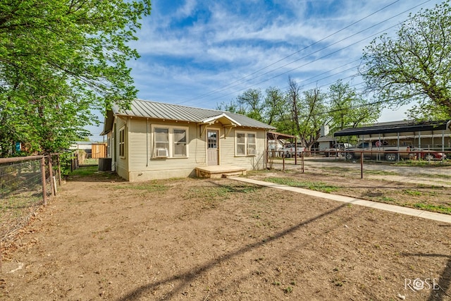 bungalow-style house with metal roof, central air condition unit, and fence