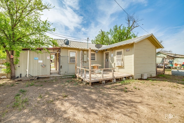 back of house featuring a wooden deck, cooling unit, and metal roof