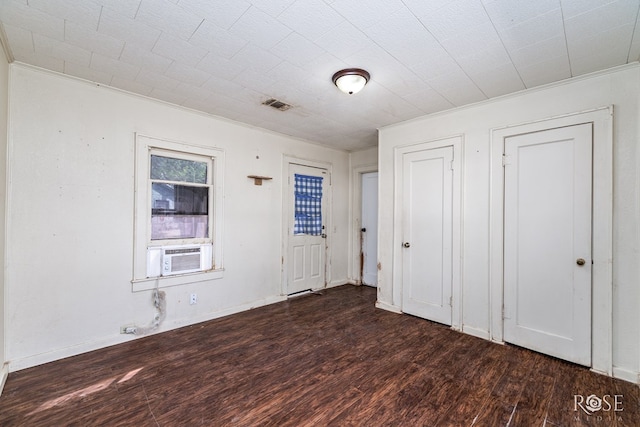 unfurnished bedroom with cooling unit, dark wood-style floors, visible vents, and ornamental molding