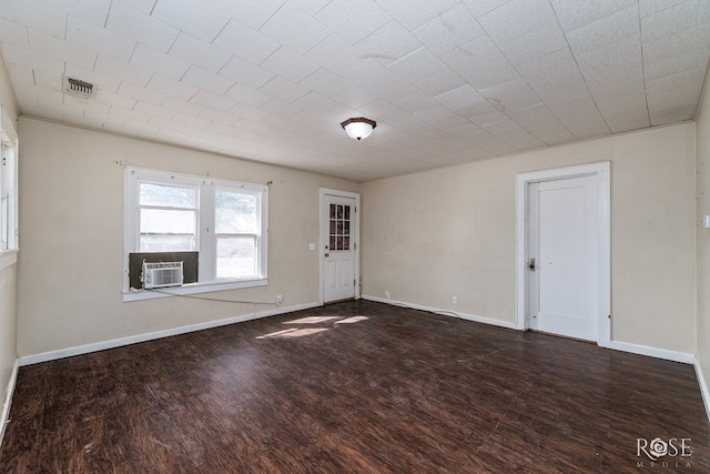 empty room with baseboards, visible vents, wood finished floors, and cooling unit