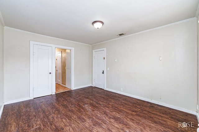 unfurnished room featuring ornamental molding, visible vents, wood finished floors, and baseboards