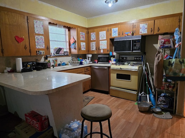 233 Robin Hood Trl, San Angelo, TX 76901 - kitchen with stainless steel appliances, a peninsula, light wood-style floors, light countertops, and brown cabinets