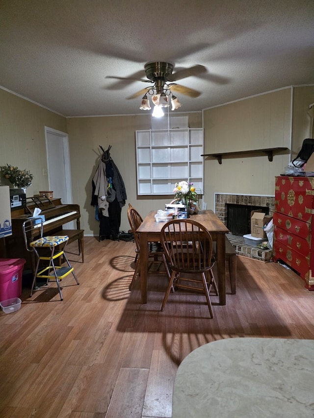 233 Robin Hood Trl, San Angelo, TX 76901 - dining space with wood finished floors, ceiling fan, a textured ceiling, a brick fireplace, and crown molding