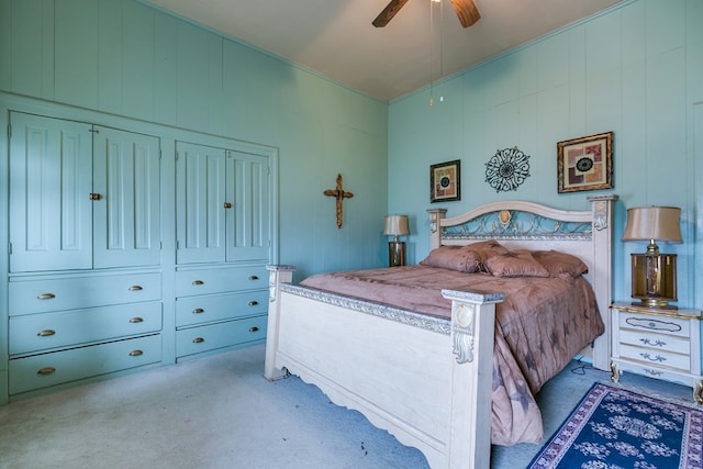 bedroom with ceiling fan, wooden walls, and light carpet