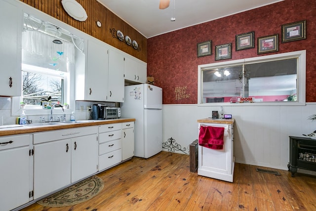 kitchen featuring sink, ceiling fan, white cabinetry, white refrigerator, and light hardwood / wood-style floors