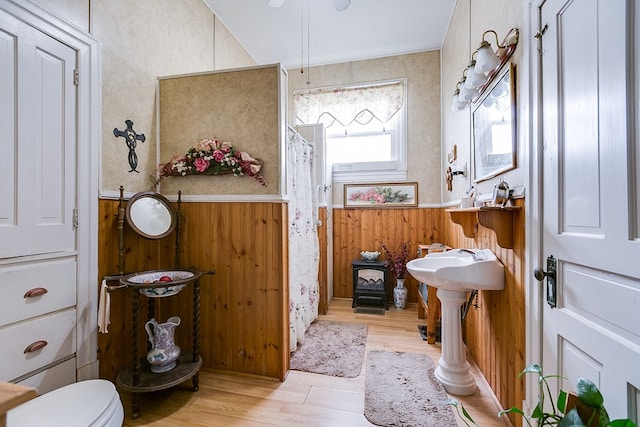 bathroom with wood-type flooring, toilet, and wood walls