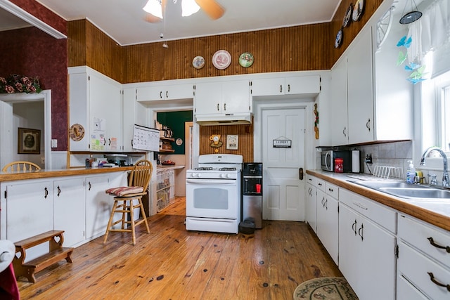 kitchen with white range with gas stovetop, white cabinets, and light hardwood / wood-style flooring