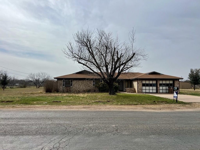 view of front of property with a front yard, brick siding, driveway, and an attached garage