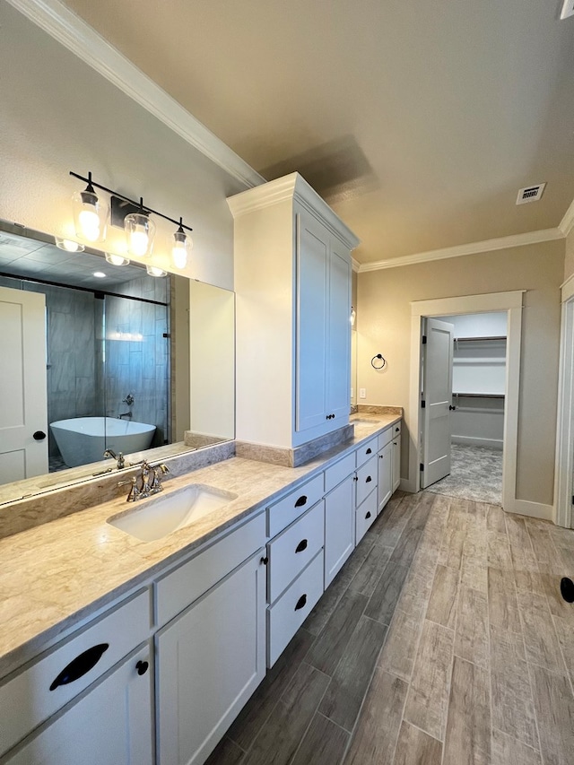 1962 Beaty Rd, San Angelo, TX 76904 - bathroom featuring wood finished floors, ornamental molding, double vanity, a soaking tub, and baseboards