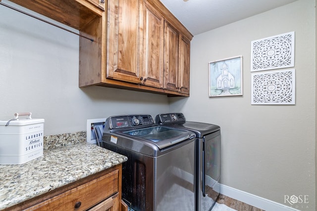 clothes washing area with cabinet space, baseboards, and washer and clothes dryer