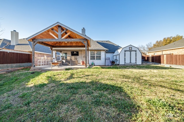 rear view of property with a patio area, a storage unit, a fenced backyard, and a yard