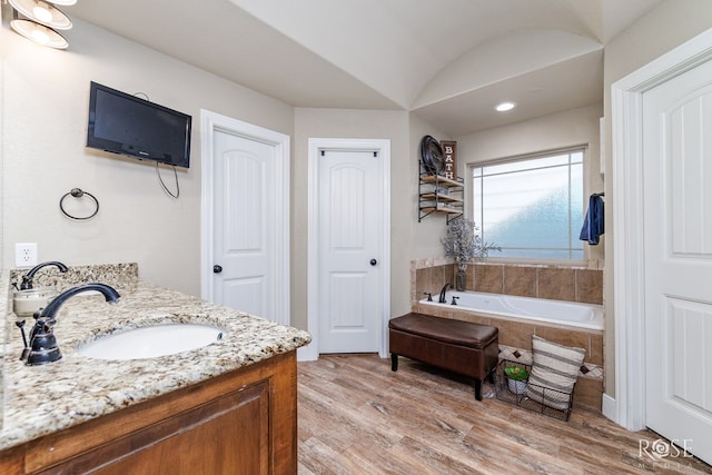 full bath with vanity, a bath, and wood finished floors