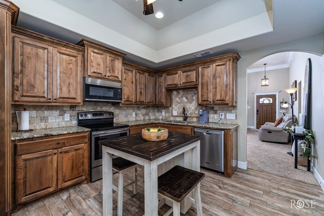 kitchen featuring visible vents, a sink, stainless steel appliances, arched walkways, and decorative backsplash