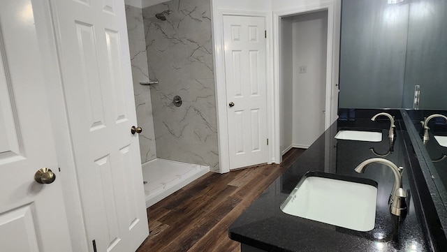 bathroom with a tile shower, vanity, and wood-type flooring