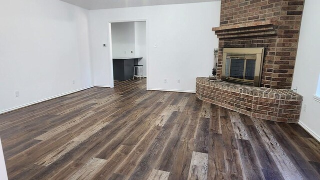 unfurnished living room featuring dark wood-type flooring and a fireplace