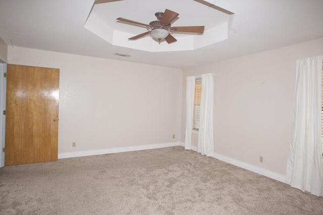 carpeted spare room with ceiling fan and a tray ceiling