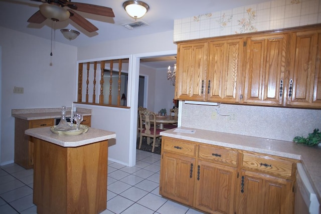 kitchen with light tile patterned floors, dishwasher, a kitchen island, ceiling fan, and backsplash