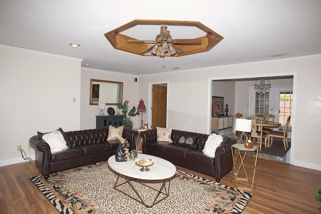 living room featuring ceiling fan with notable chandelier, wood-type flooring, and ornamental molding