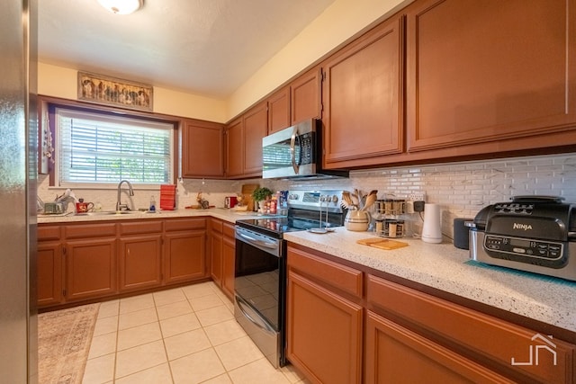 kitchen featuring light tile patterned floors, decorative backsplash, stainless steel appliances, and sink