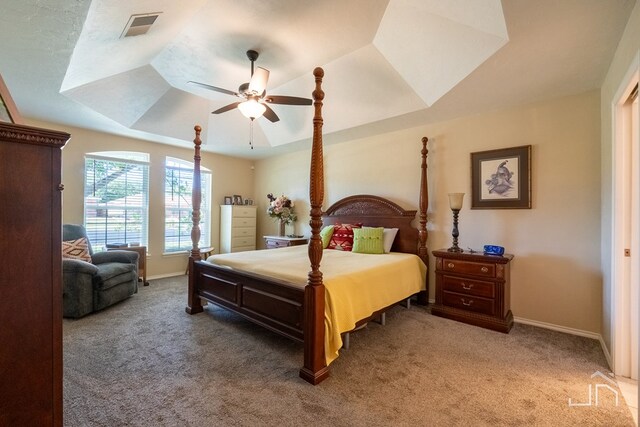 bedroom featuring a raised ceiling, carpet flooring, and ceiling fan