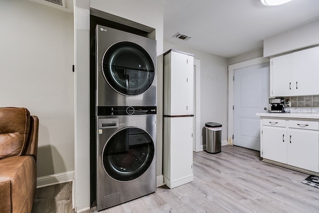 laundry room featuring light hardwood / wood-style floors and stacked washer / dryer