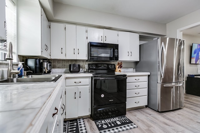 kitchen featuring sink, white cabinetry, black appliances, light hardwood / wood-style flooring, and backsplash