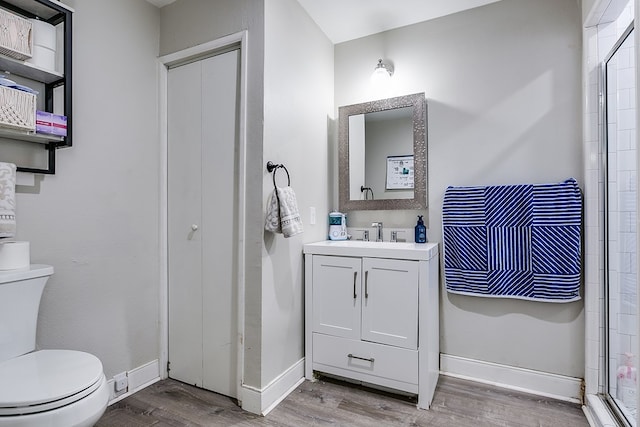 bathroom featuring hardwood / wood-style flooring, vanity, toilet, and walk in shower