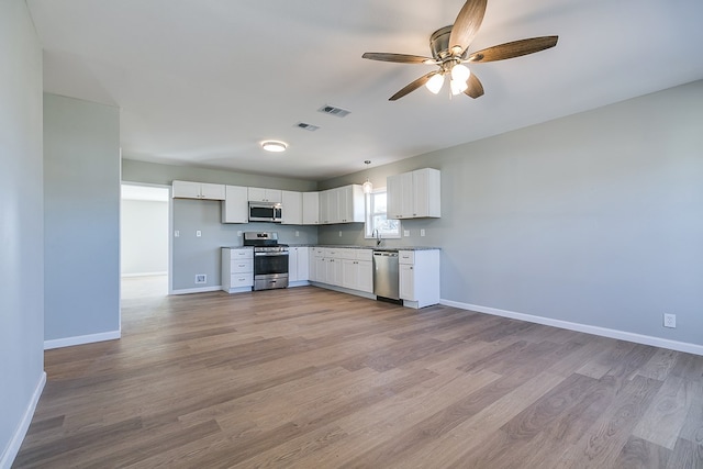 kitchen with stainless steel appliances, white cabinets, ceiling fan, and light hardwood / wood-style flooring