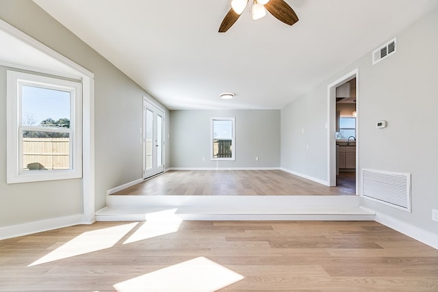 unfurnished room with ceiling fan, sink, a wealth of natural light, and light wood-type flooring