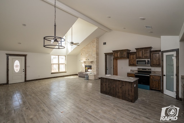 kitchen with a center island, a fireplace, appliances with stainless steel finishes, ceiling fan, and wood finished floors