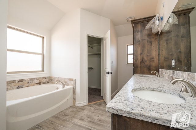 full bath featuring wood finish floors, visible vents, a sink, and a bath