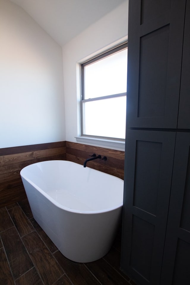 9614 Bighorn Trl, San Angelo, TX 76901 - full bath with a freestanding bath, lofted ceiling, a wainscoted wall, tile walls, and wood finish floors