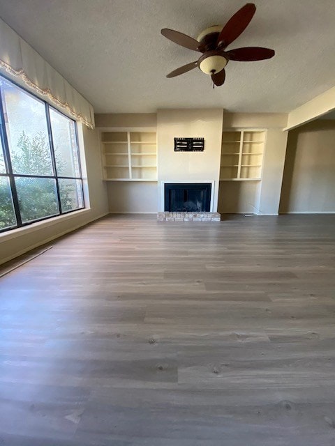 unfurnished living room with a fireplace with raised hearth, a textured ceiling, and wood finished floors