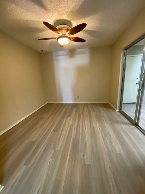 empty room featuring a textured ceiling, wood finished floors, and baseboards