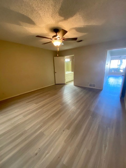 spare room with visible vents, a textured ceiling, baseboards, and wood finished floors