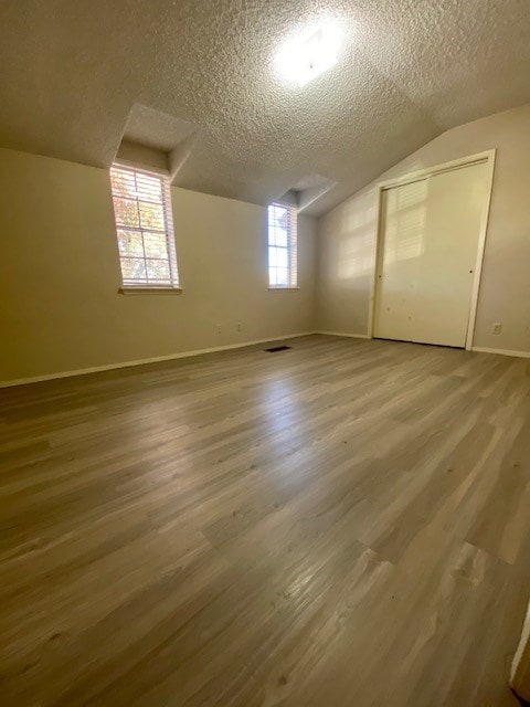 bonus room with lofted ceiling, a textured ceiling, and wood finished floors