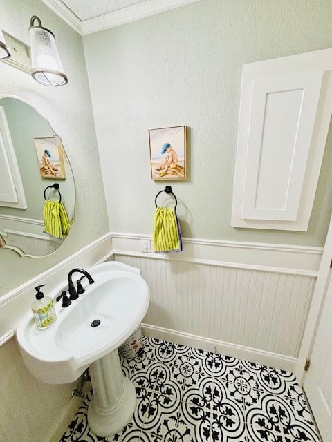 bathroom with tile patterned floors, ornamental molding, and a wainscoted wall