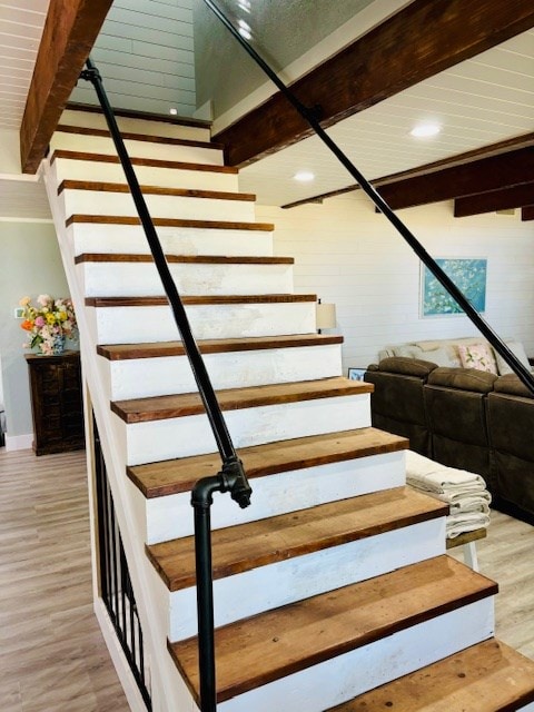stairway with recessed lighting, baseboards, wood finished floors, and beamed ceiling