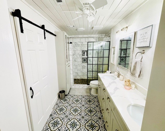 full bath with double vanity, a sink, ceiling fan, and a stall shower