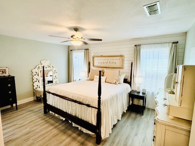 bedroom featuring visible vents, a ceiling fan, a textured ceiling, and light wood-type flooring