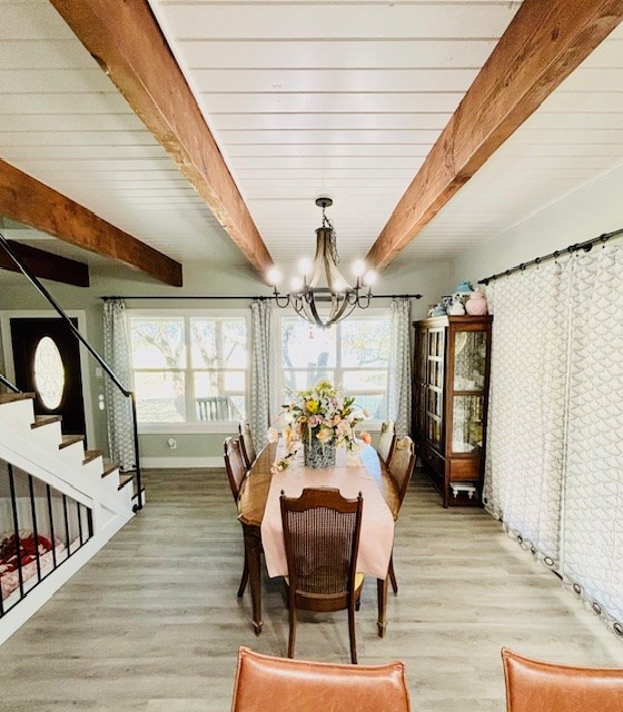 dining space with an inviting chandelier, light wood-type flooring, beam ceiling, and a healthy amount of sunlight