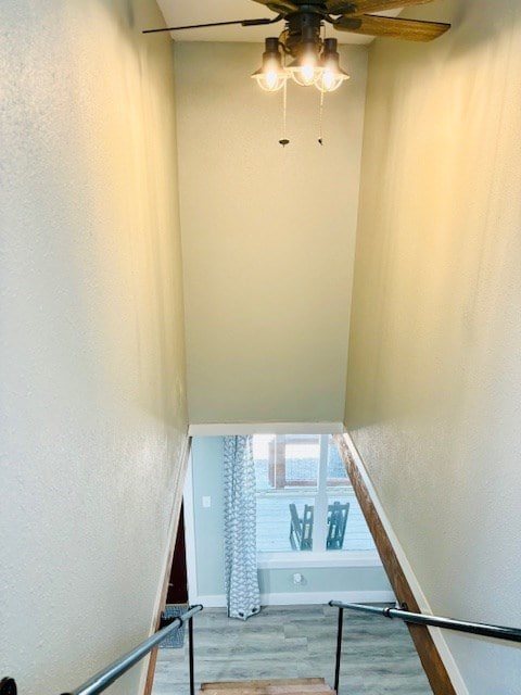 staircase featuring baseboards, a ceiling fan, and wood finished floors