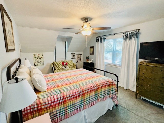 bedroom with ceiling fan, lofted ceiling, and carpet
