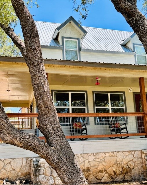 rear view of property featuring covered porch and metal roof